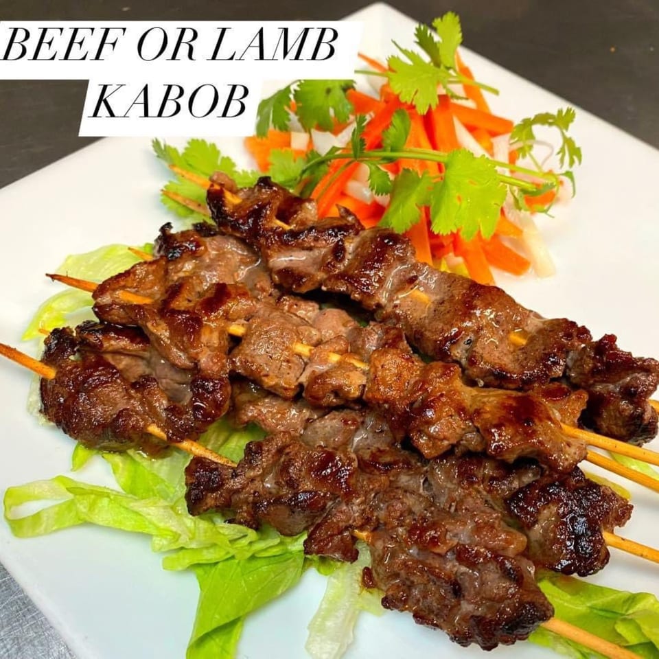 Grilled beef or lamb kabobs on skewers, served with fresh lettuce and a side of pickled vegetables.