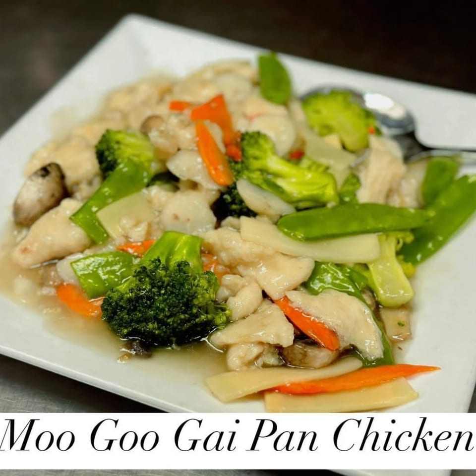 Moo Goo Gai Pan Chicken with broccoli, carrots, and mushrooms on a white plate.