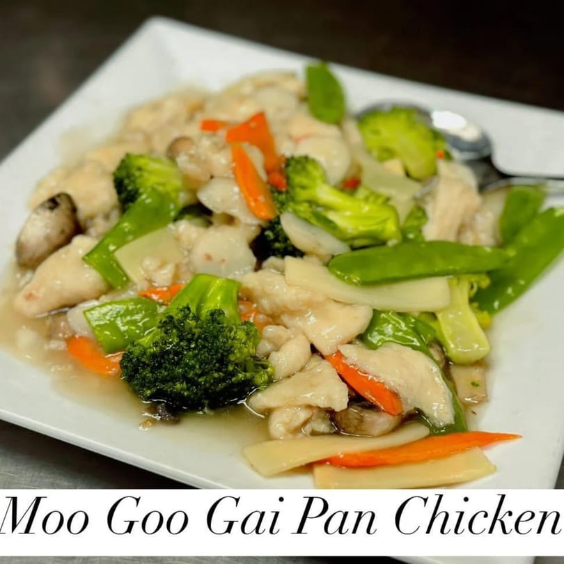 Moo Goo Gai Pan Chicken with broccoli, carrots, and mushrooms on a white plate.