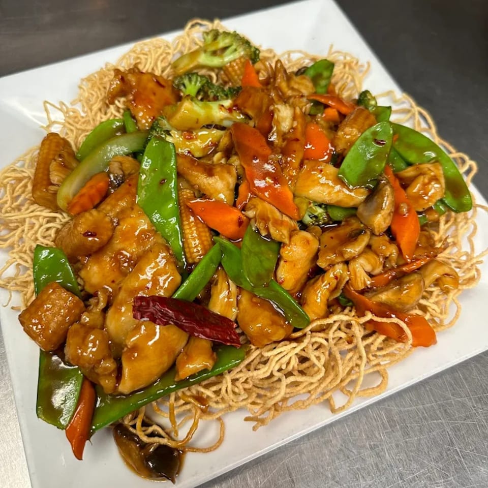 Asian Bistro's chicken stir-fry with vegetables and crispy noodles on a white plate.