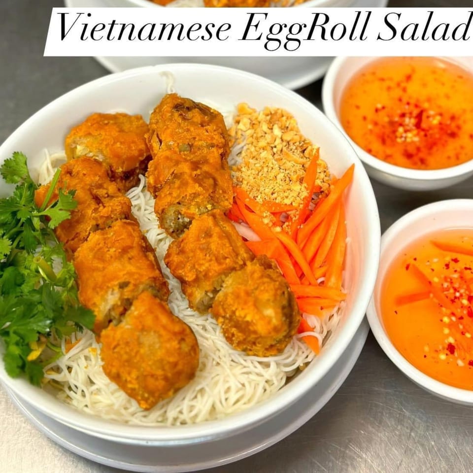 Vietnamese EggRoll Salad with crispy egg rolls, vermicelli noodles, carrots, peanuts, and cilantro, with dipping sauce.