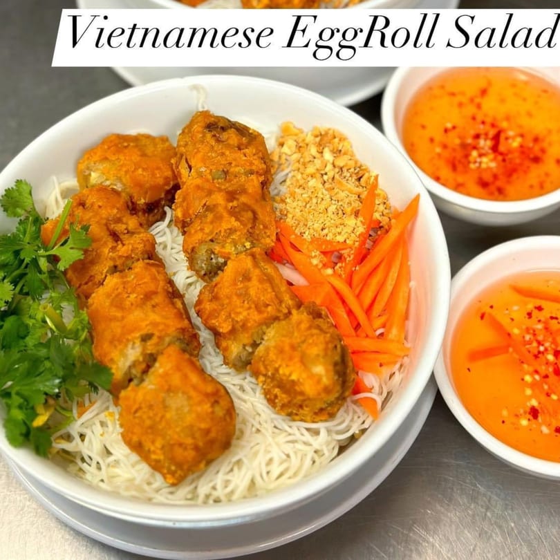 Vietnamese EggRoll Salad with crispy egg rolls, vermicelli noodles, carrots, peanuts, and cilantro, with dipping sauce.
